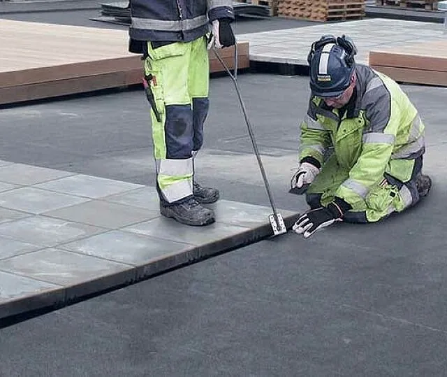 To arbeidere legger betongheller på ferdig takmembran